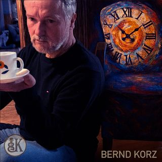 "Ein Mann mit einer Tasse in der Hand, der an einem Sessel lehnt. Der Sitz beinhaltet eine Uhr"